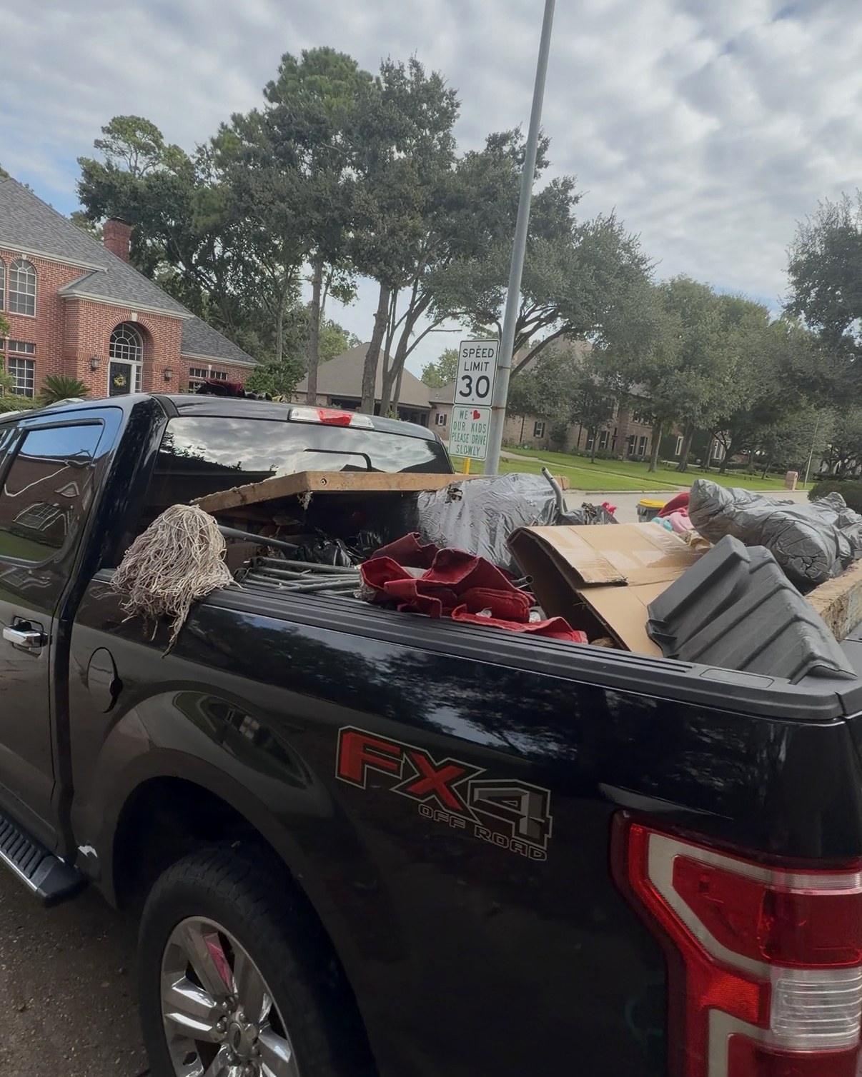 Outlaw Junk & Yard pickup loaded with junk on a residential street in Spring, Texas