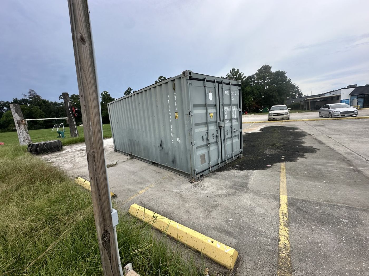 Grey shipping container on a commercial lot being cleared